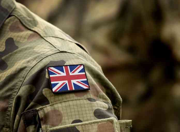 Shoulder of a solider in camouflage uniform with the British flag.